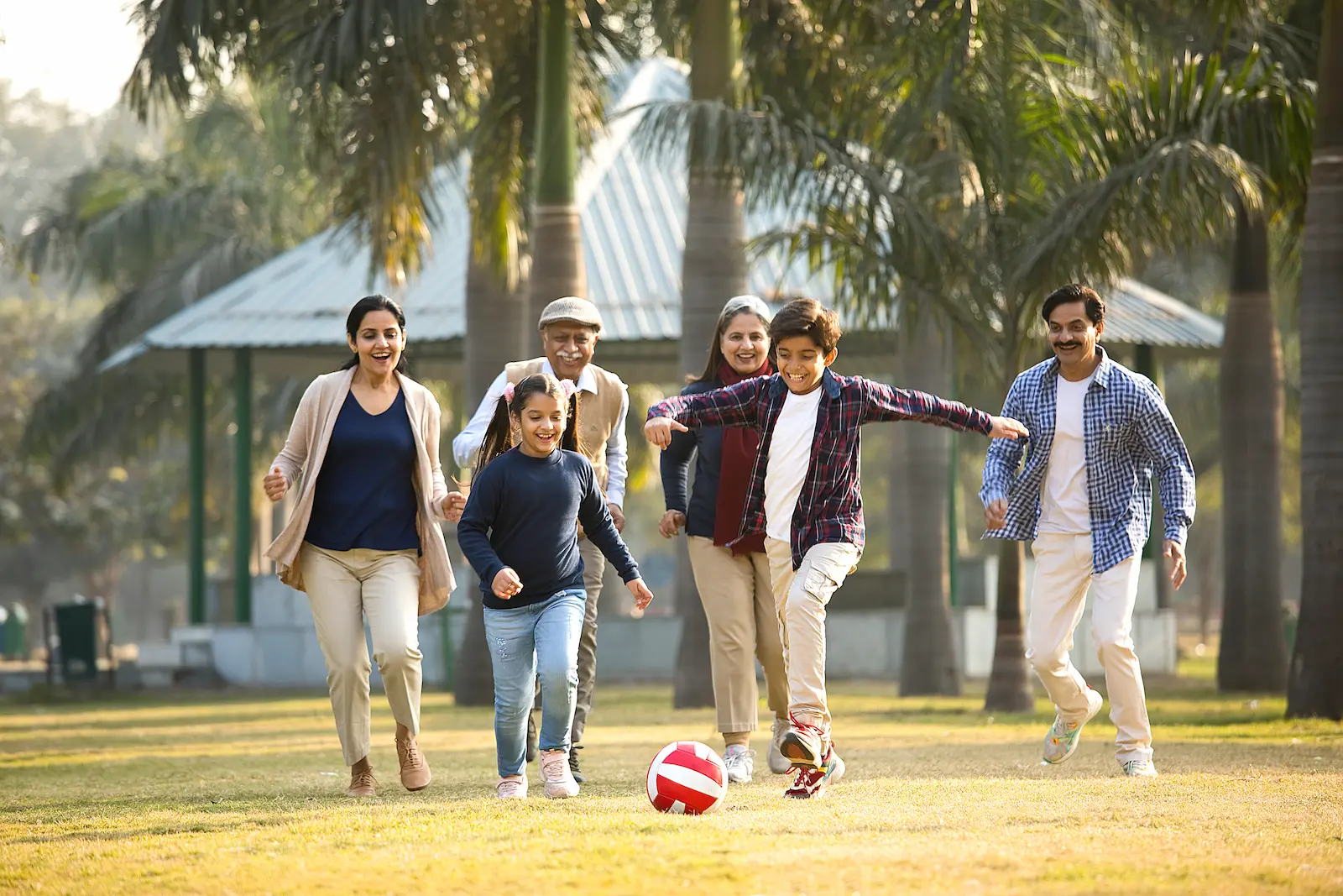 A multigenerational family playing football together in a park